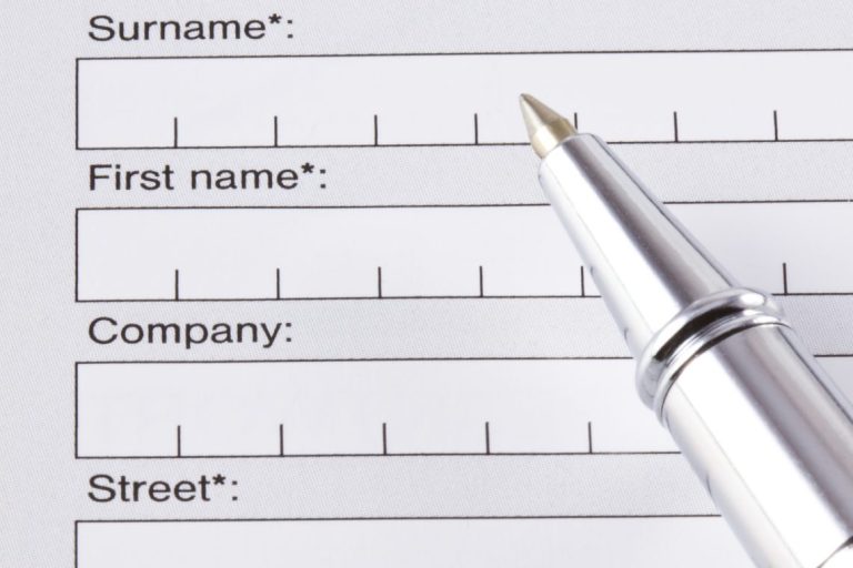 Formulario en blanco con campos para apellidos, nombre, compañía y dirección, junto a un bolígrafo.