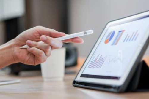 Mano sosteniendo un lápiz señalando gráficos de la auditoría retributiva en una tablet sobre una mesa.